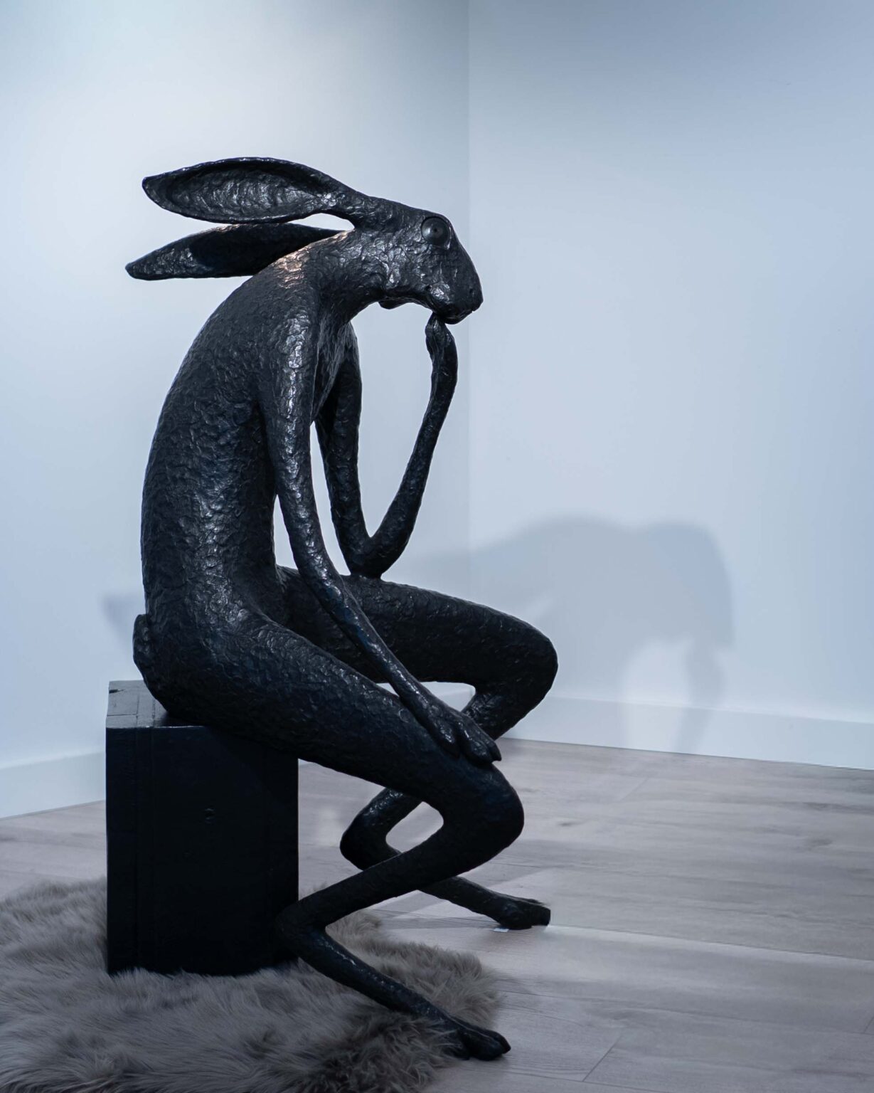 Cette sculpture en bronze à patine noire représente un lapin assis sur ses pattes arrière, dans un style figuratif et humoristique. Il semble réfléchir profondément, comme le « Penseur » de Rodin.