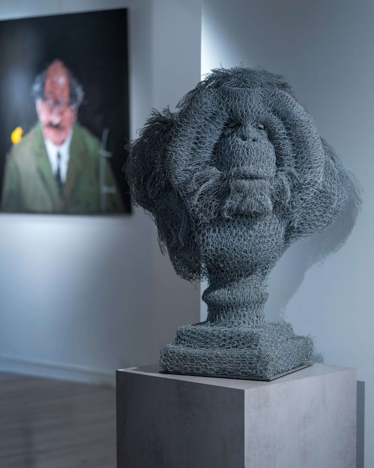 Cette sculpture animalière, réalisée en grillage galvanisé, représente un orang-outan posé sur un piédestal.