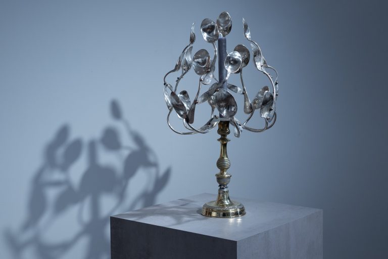 Sculpture en argenterie et laiton, « Buisson ardent sur les dunes » déploie un buisson de cuillères comme des flammes figées dans la lumière, évoquant une apparition mystique au cœur d’un désert contemporain.